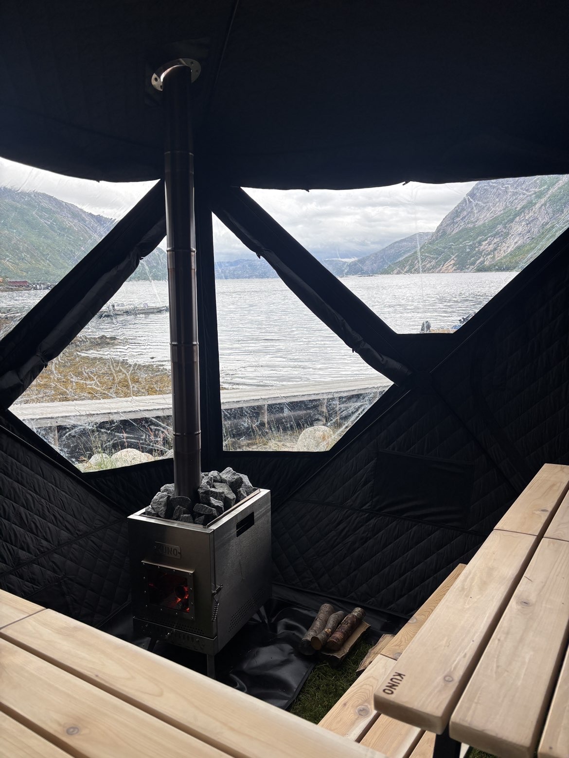 Innvendig med vedovn og fjordutsikt gjennom panoramavinduer